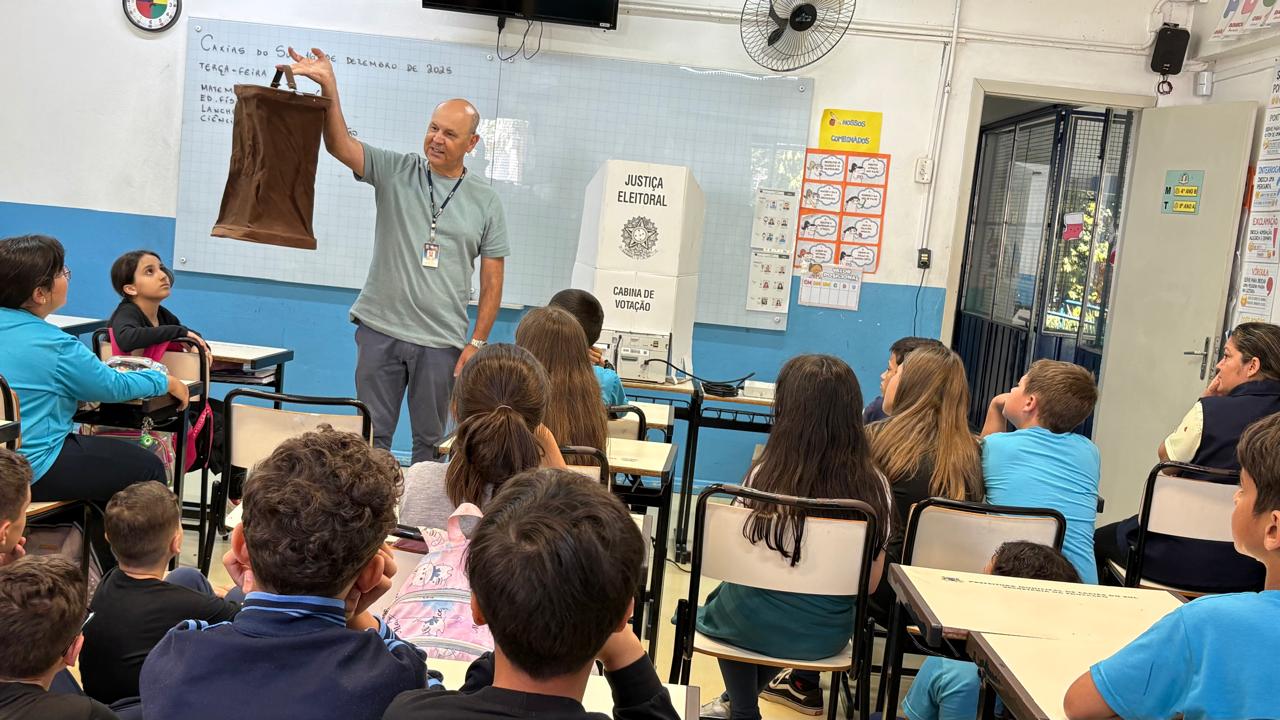 palestrante mostrando para os alunos a urna de lona