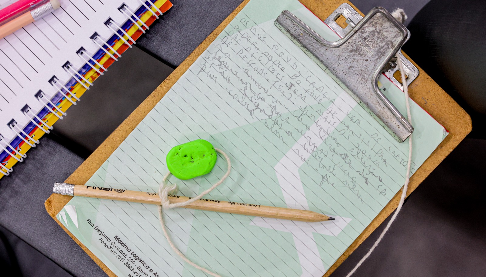 uma prancheta com folha, um lápis em cima e uma borracha cor verde.
